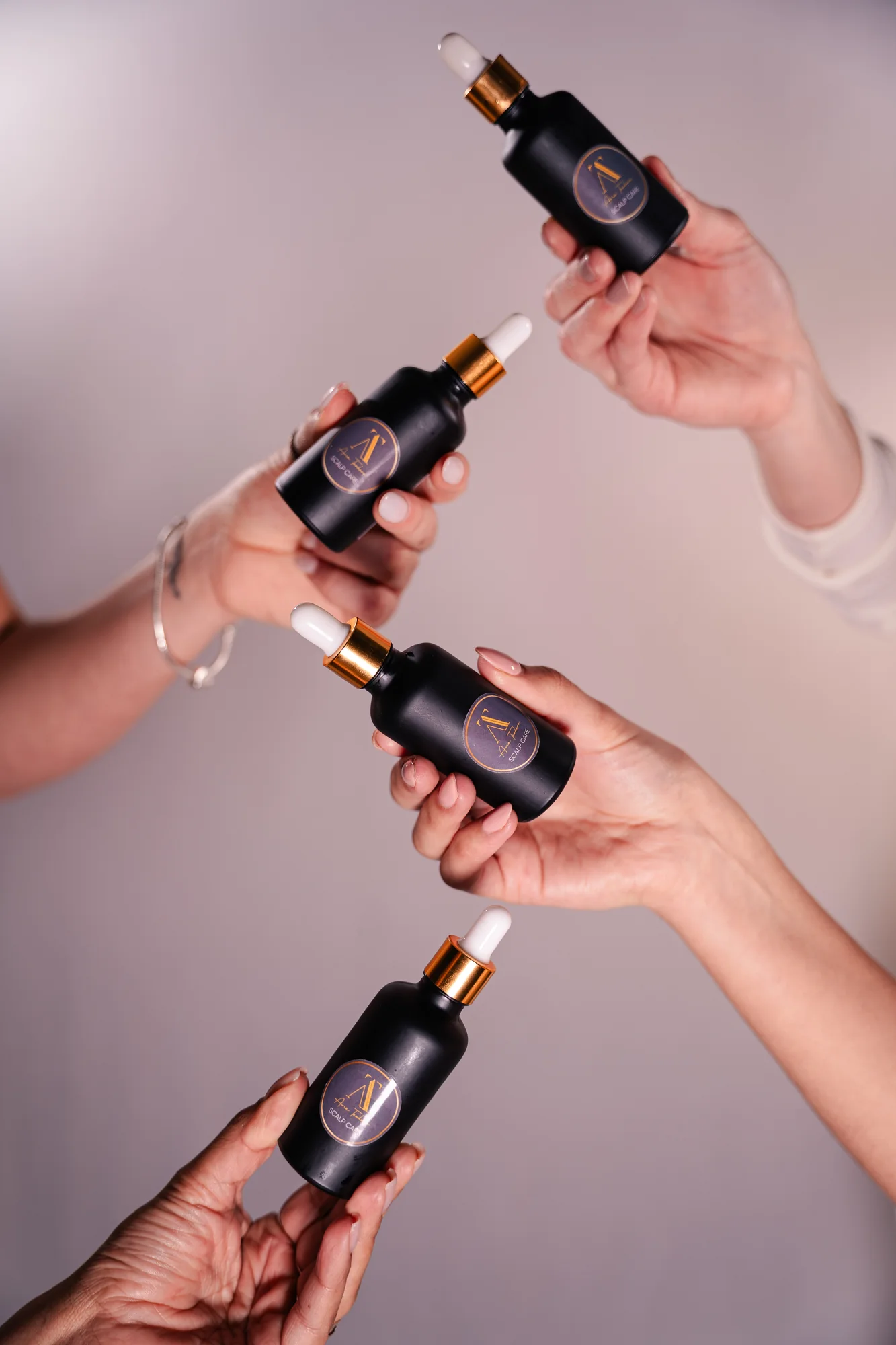 Hands presenting bottles of the hair tonic product