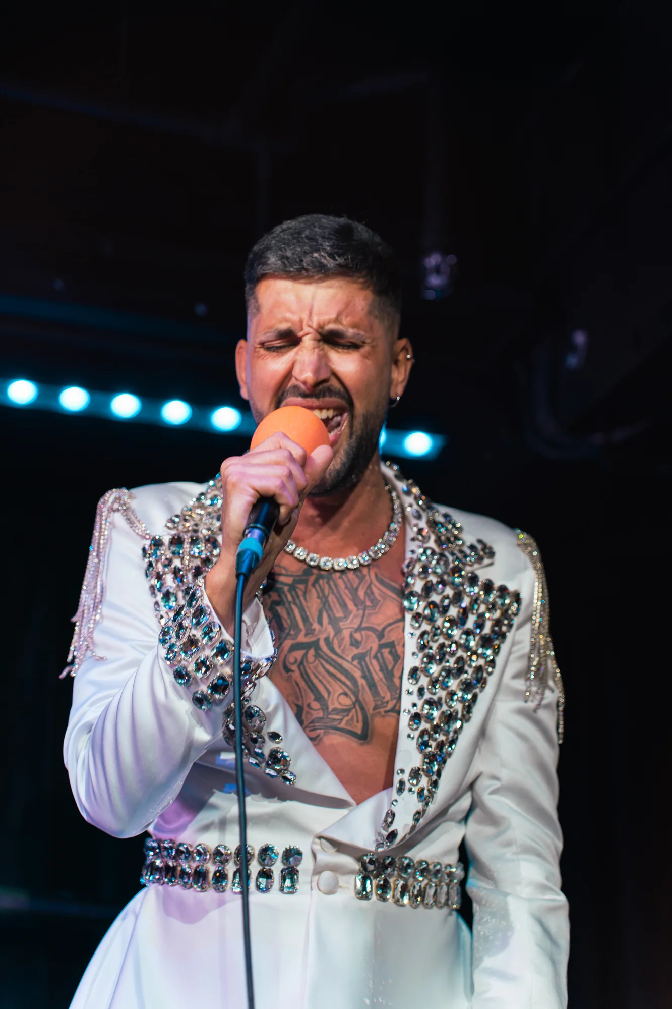 Performer singing in an embellished white jacket
